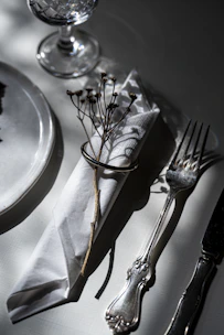 Elegant table setting with white plates, crystal glasses, and polished cutlery arranged for a wedding reception.