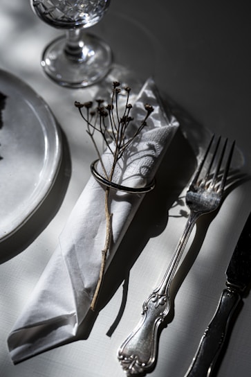 Elegant table setting with white dishes, silverware, and crystal glassware arranged for a wedding reception.