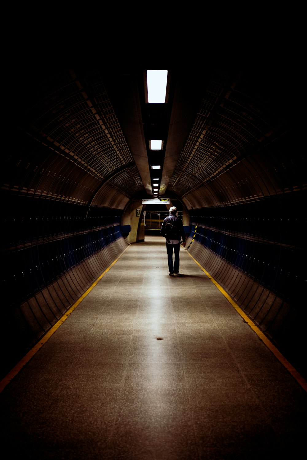 man in black jacket walking on tunnel