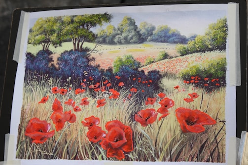 A vibrant painting depicts a scenic landscape with a field full of red poppies. There are patches of tall grasses, lush green trees, and a distant horizon lined with more flowers and foliage. The artwork captures a peaceful and serene rural scene under a clear blue sky.