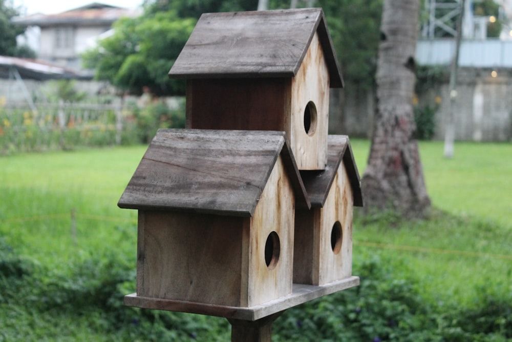 brown wooden birdhouse on green grass field during daytime