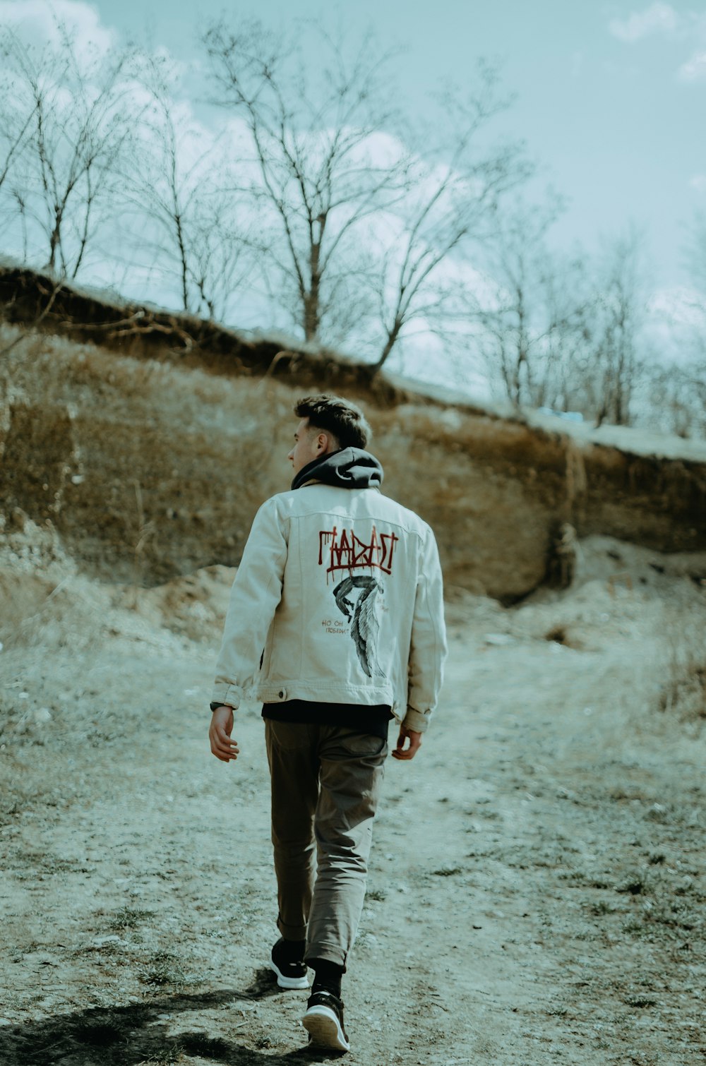 man in gray hoodie standing on gray dirt road during daytime