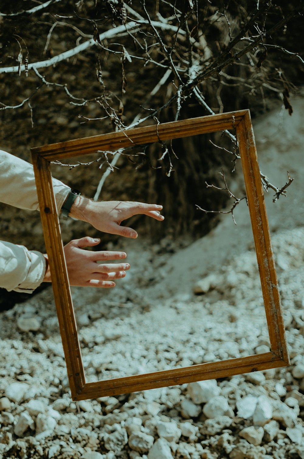 person in white long sleeve shirt holding brown wooden frame