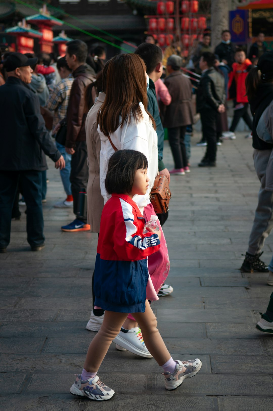 girl in white long sleeve shirt and red skirt standing on gray concrete floor