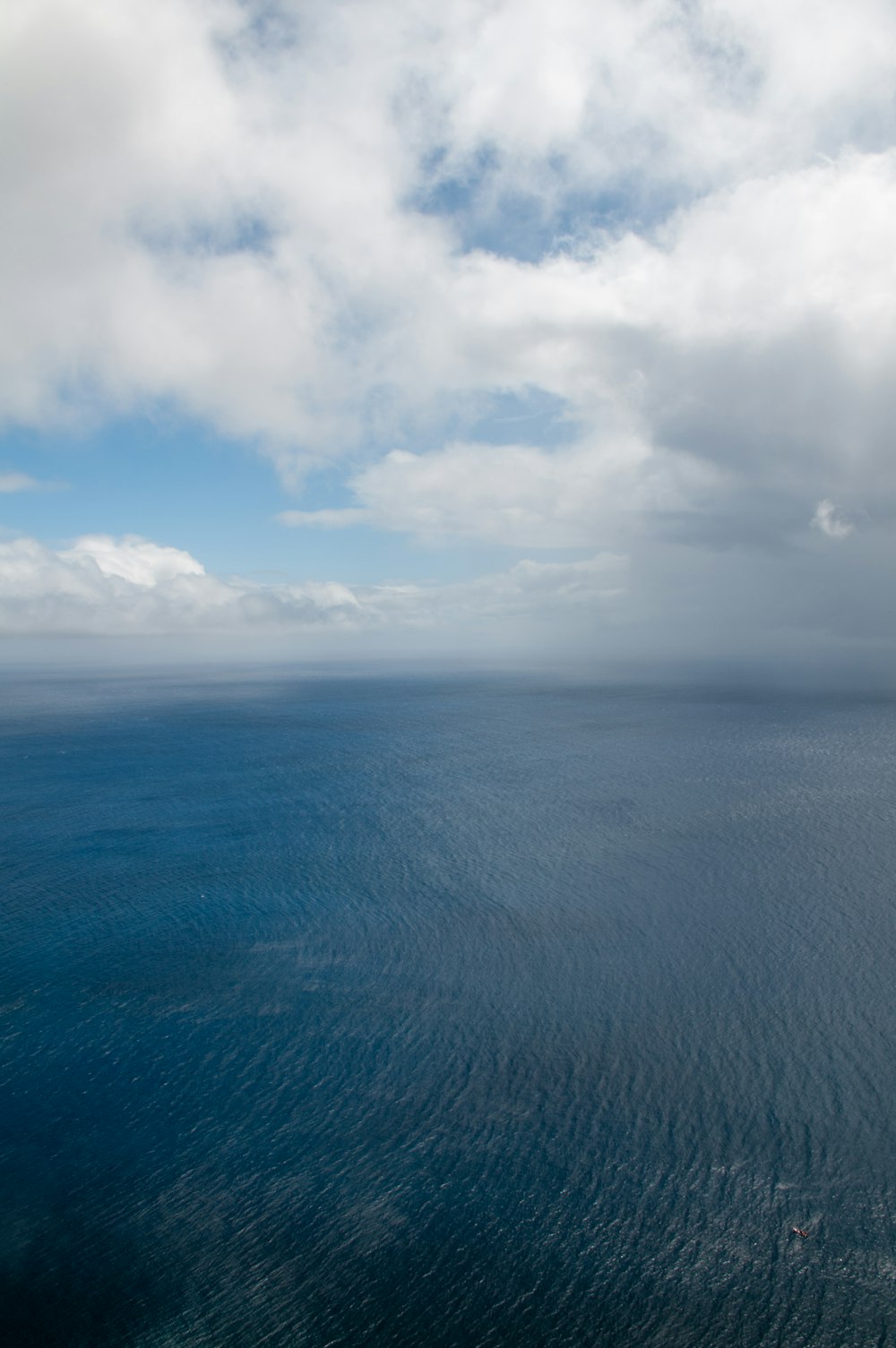 oceano azul sob nuvens brancas durante o dia