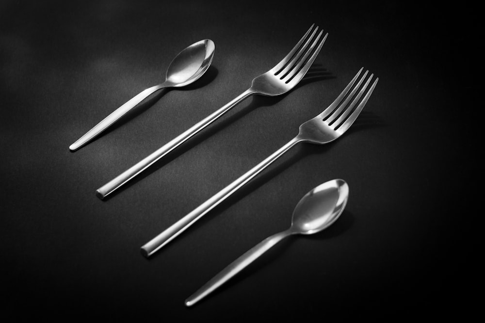 silver spoon and fork on black surface