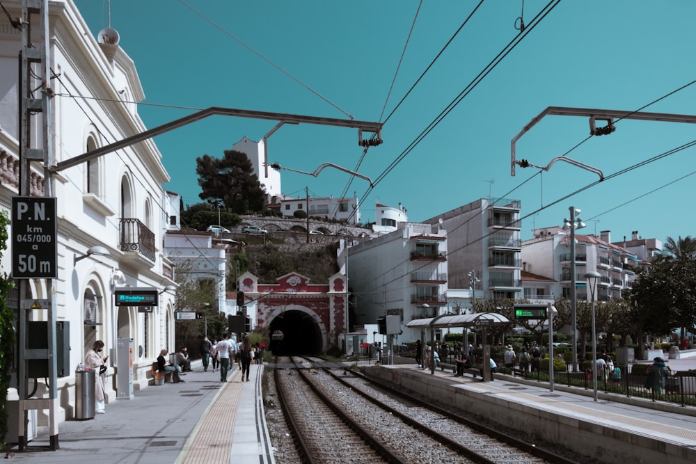 Train rouge sur la voie ferrée près d’un bâtiment en béton blanc pendant la journée