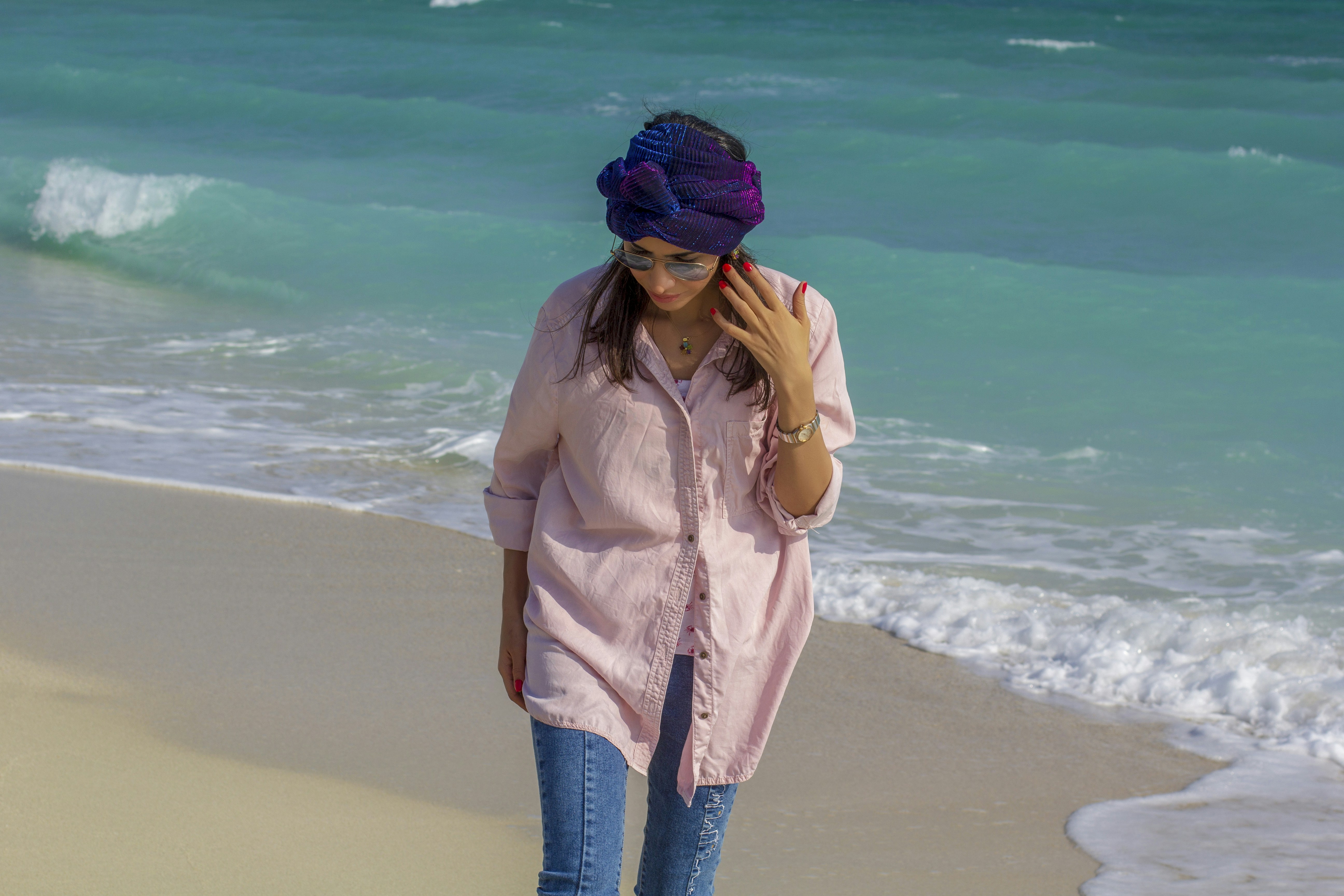 woman in brown jacket and blue denim jeans standing on beach during daytime