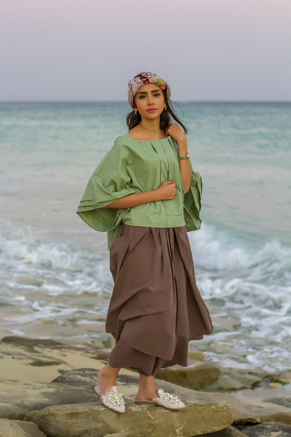 Mujer en vestido verde de pie en la playa durante el día