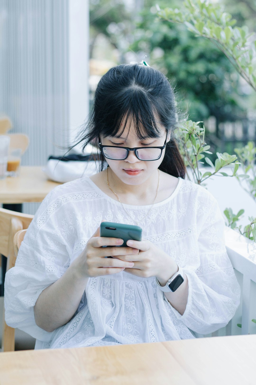 woman in white button up shirt holding green smartphone