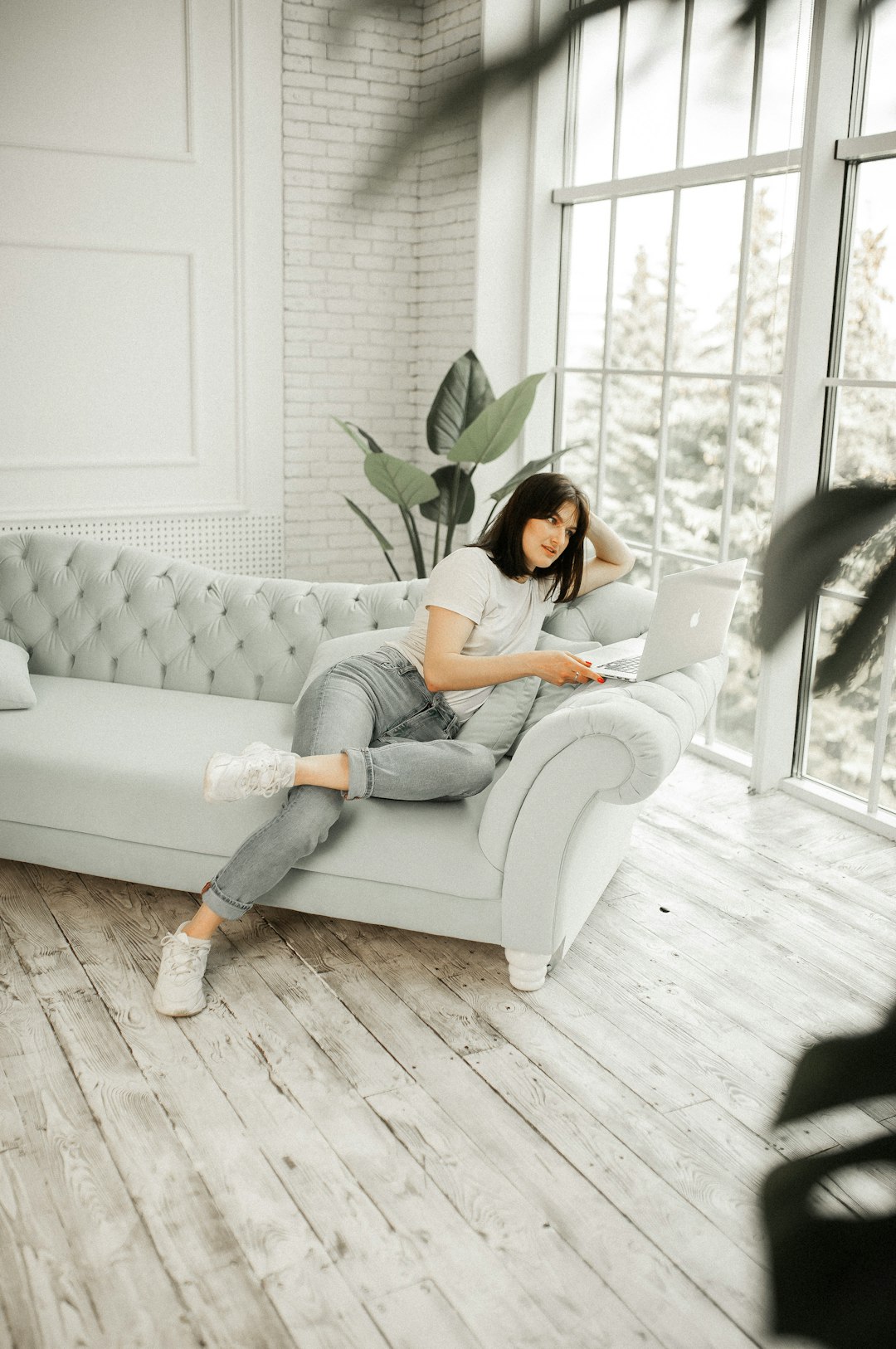 woman in white shirt and blue denim jeans sitting on white couch