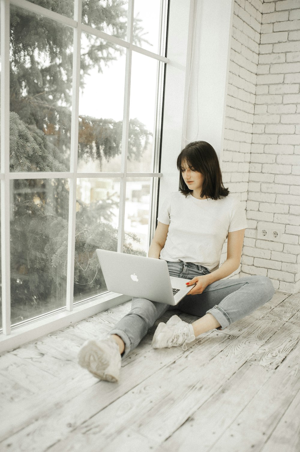 woman in white shirt using macbook