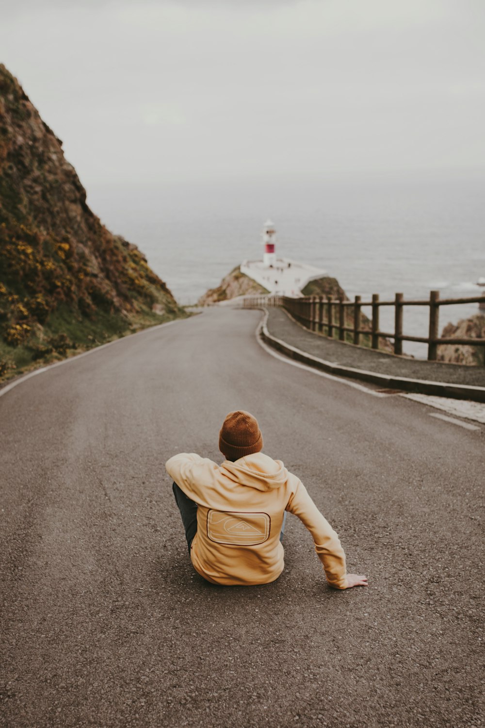 person in brown jacket and brown pants sitting on gray concrete road during daytime