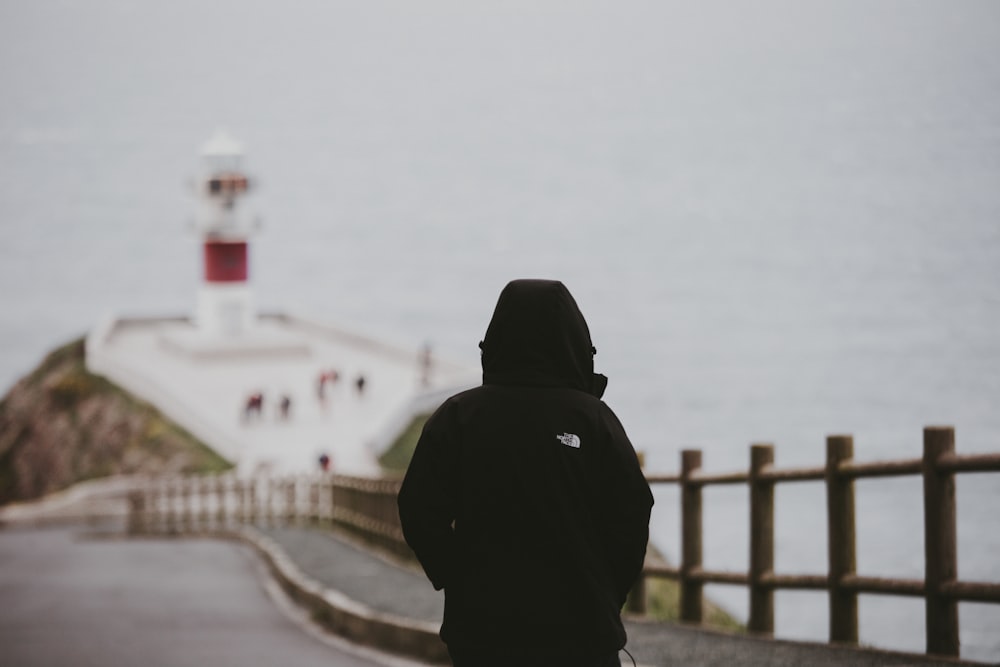 person in black hoodie standing on road during daytime