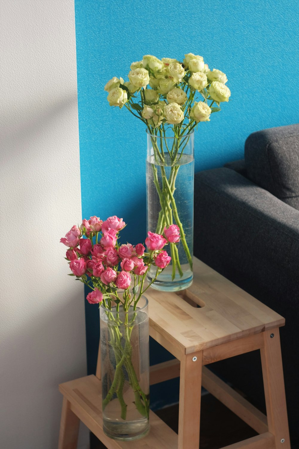 gelbe und rosa Blumen in klarer Glasvase auf braunem Holztisch