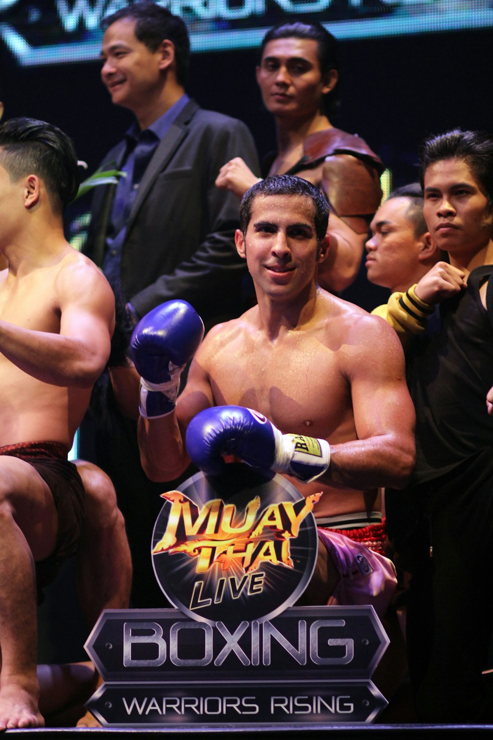 topless man in red shorts holding blue and black boxing gloves