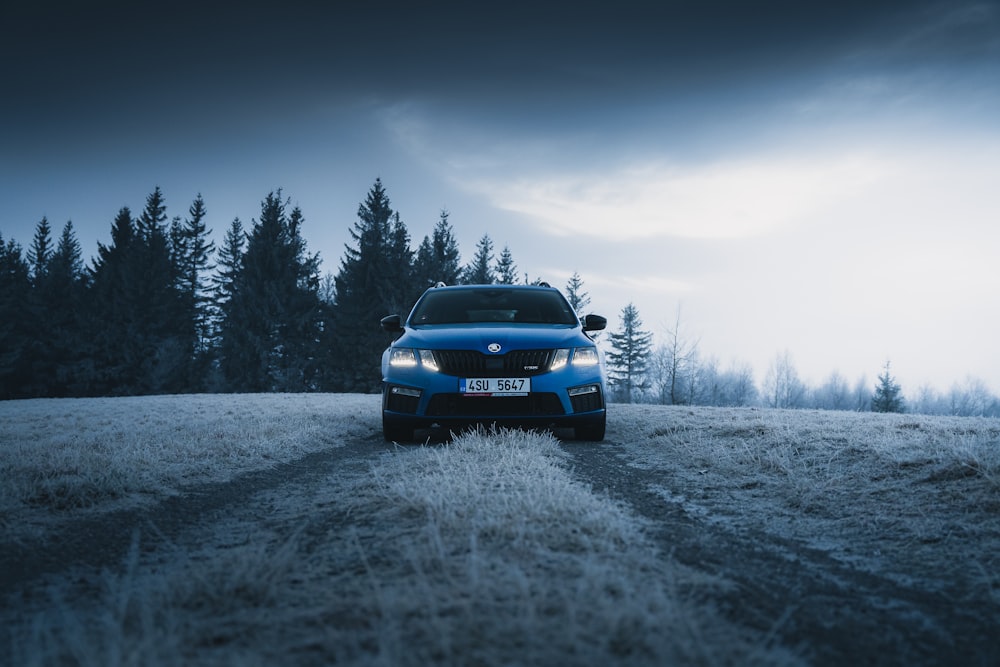 coche azul en un campo cubierto de nieve durante el día