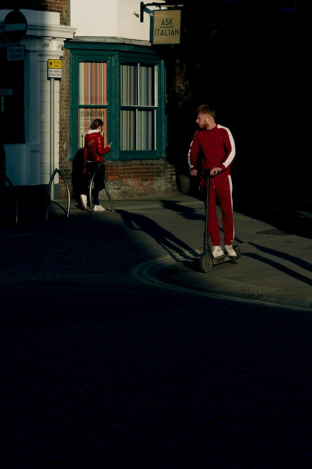 빨간 셔츠와 바지를 입은 남자가 낮에 개와 함께 걷고 있다