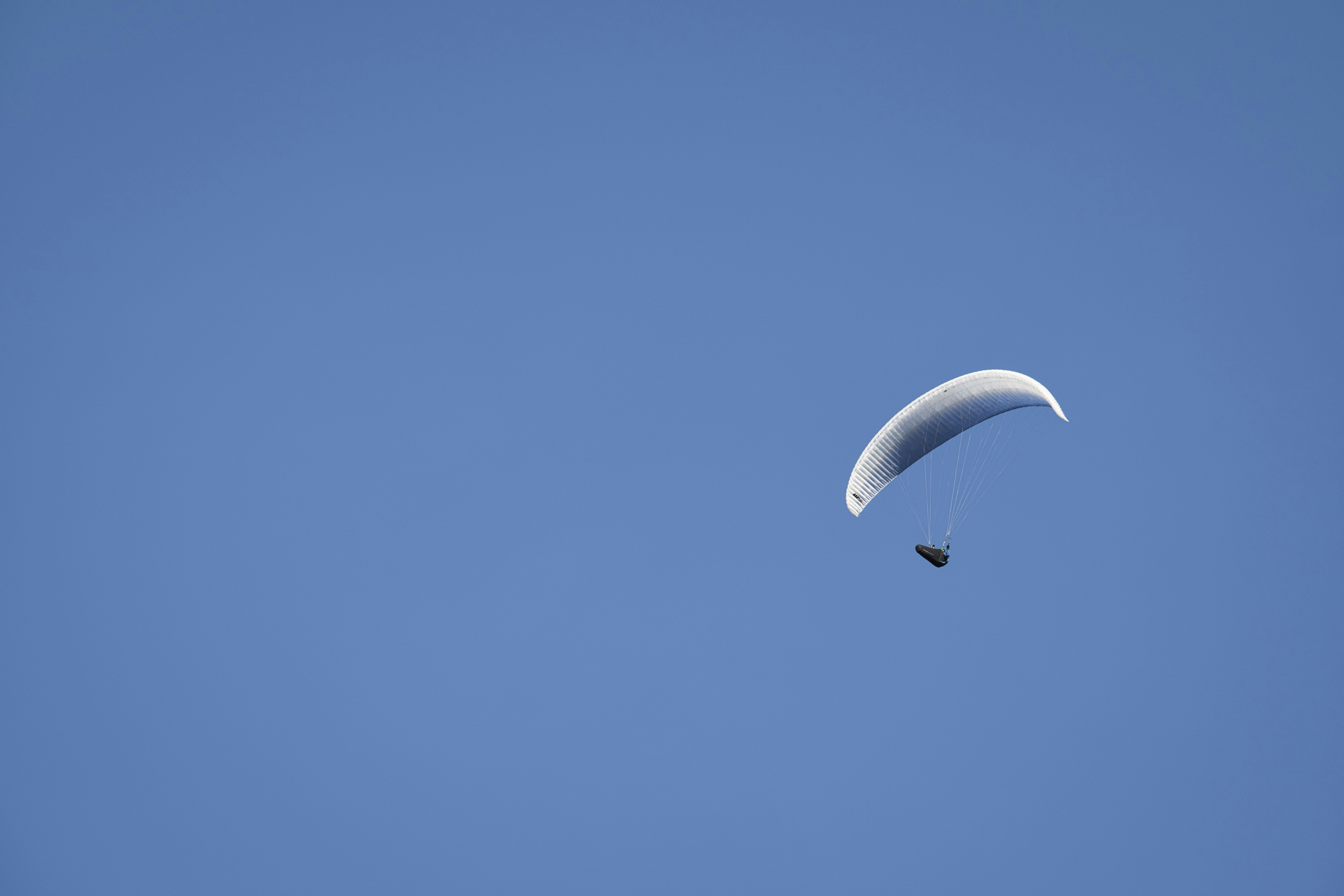 person in white parachute under blue sky during daytime
