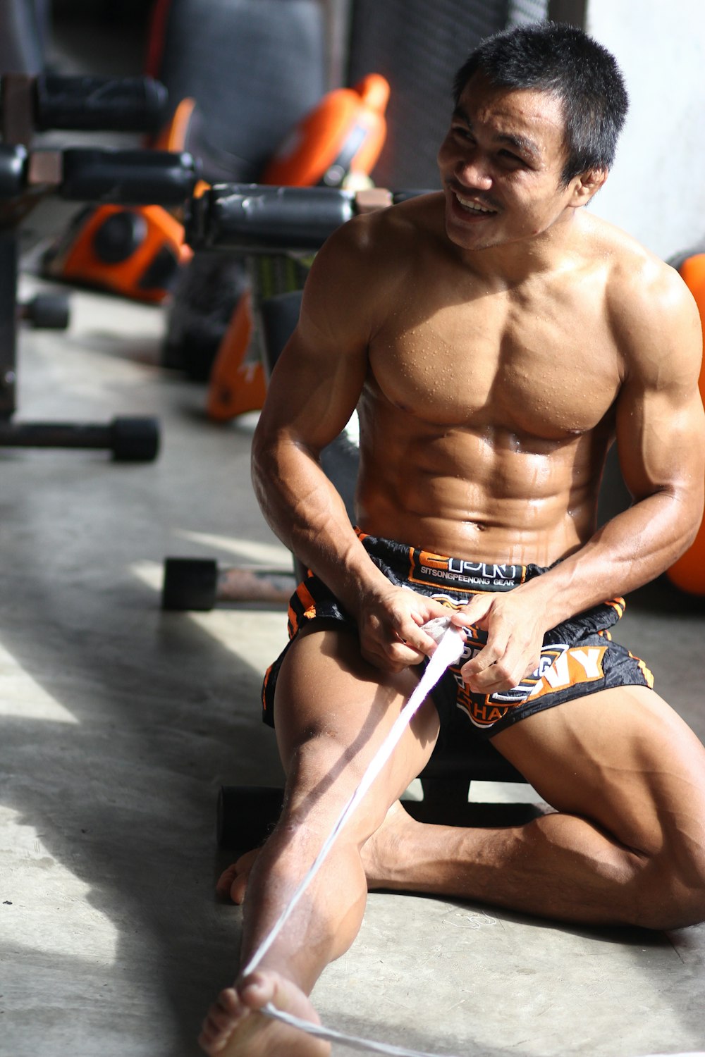 topless man in black and white shorts sitting on black and white exercise equipment