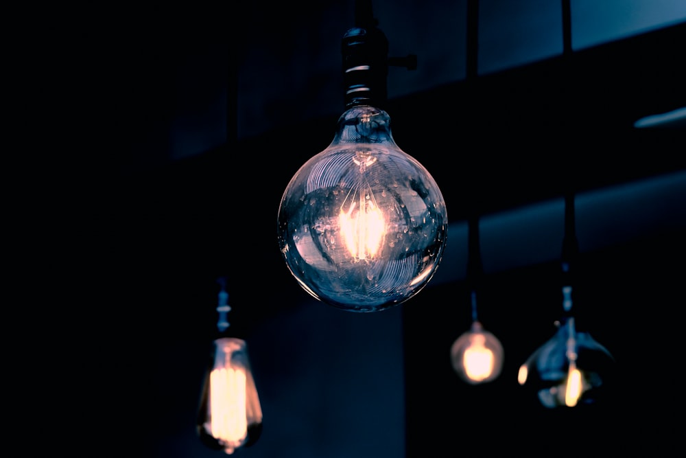 clear glass light bulb turned on in dim lit room