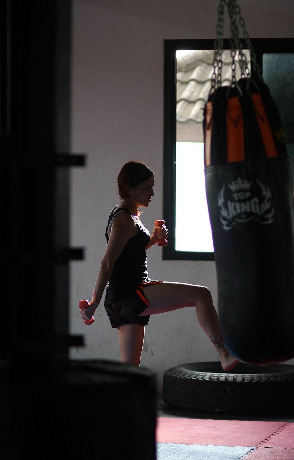 woman in black tank top and black shorts sitting on black heavy bag