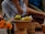 Close-up of hands carefully arranging ceremonial paper offerings on a wooden table.