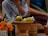Close-up of hands carefully arranging ceremonial paper offerings on a wooden table.
