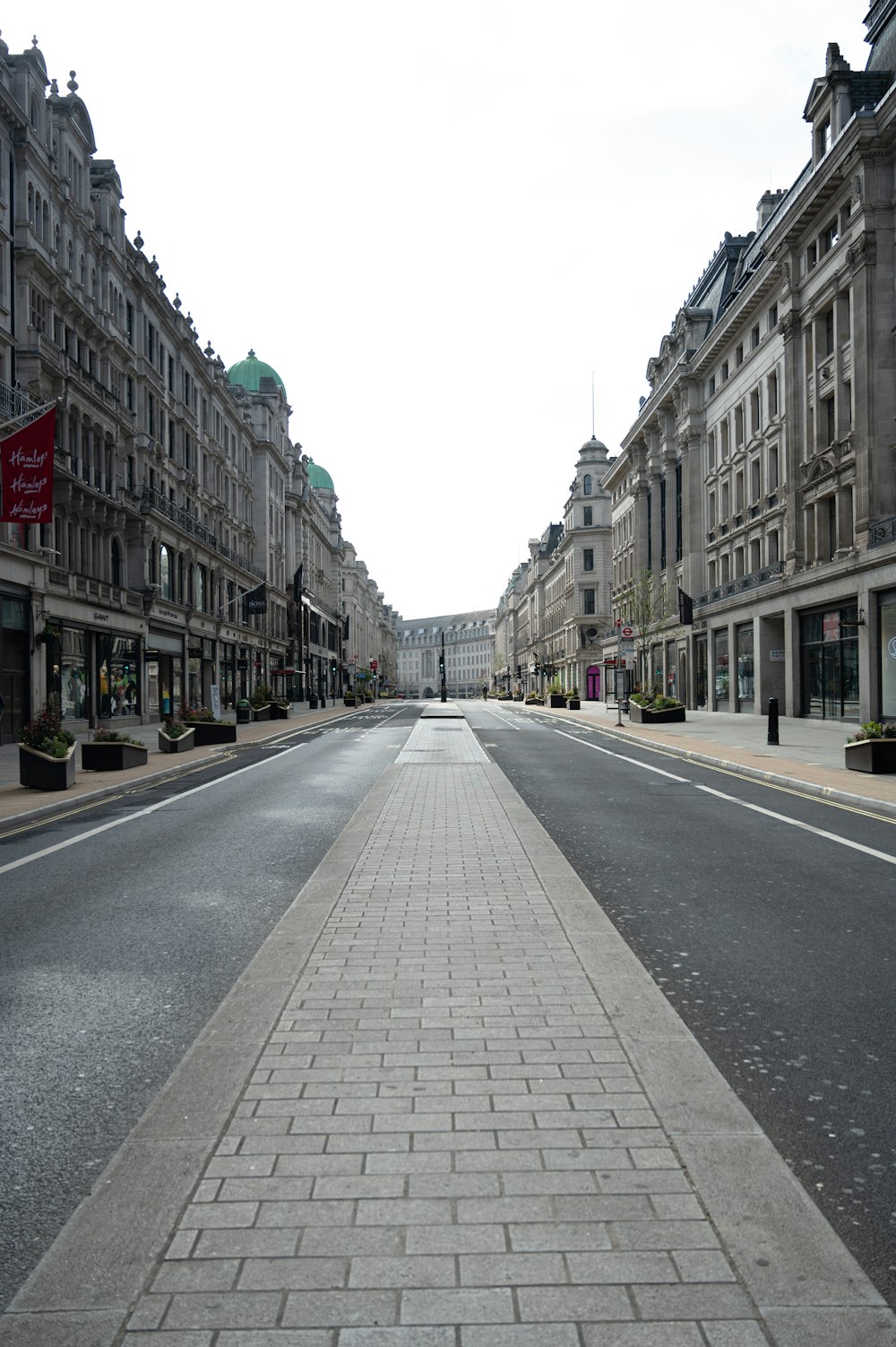 日中の茶色のコンクリートの建物の間の灰色のコンクリート道路