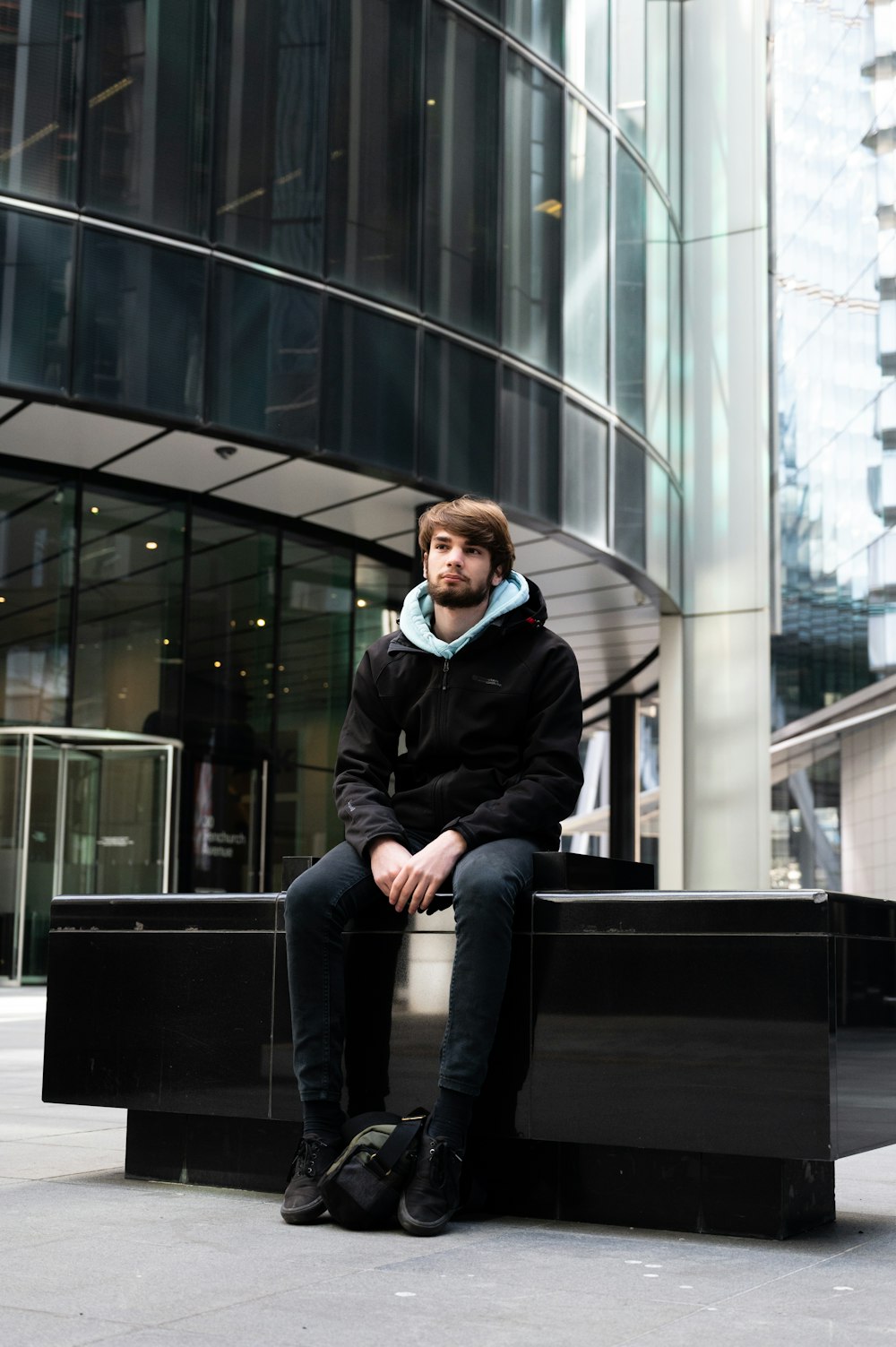 man in black jacket sitting on black bench