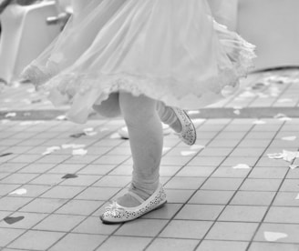 grayscale photo of woman in white dress and black and white converse all star high top