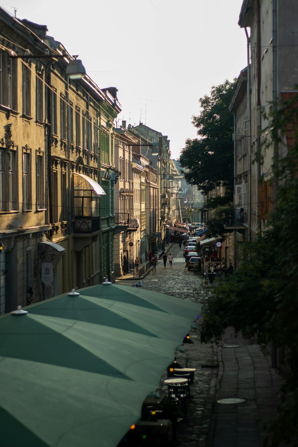 green umbrella on sidewalk near buildings during daytime