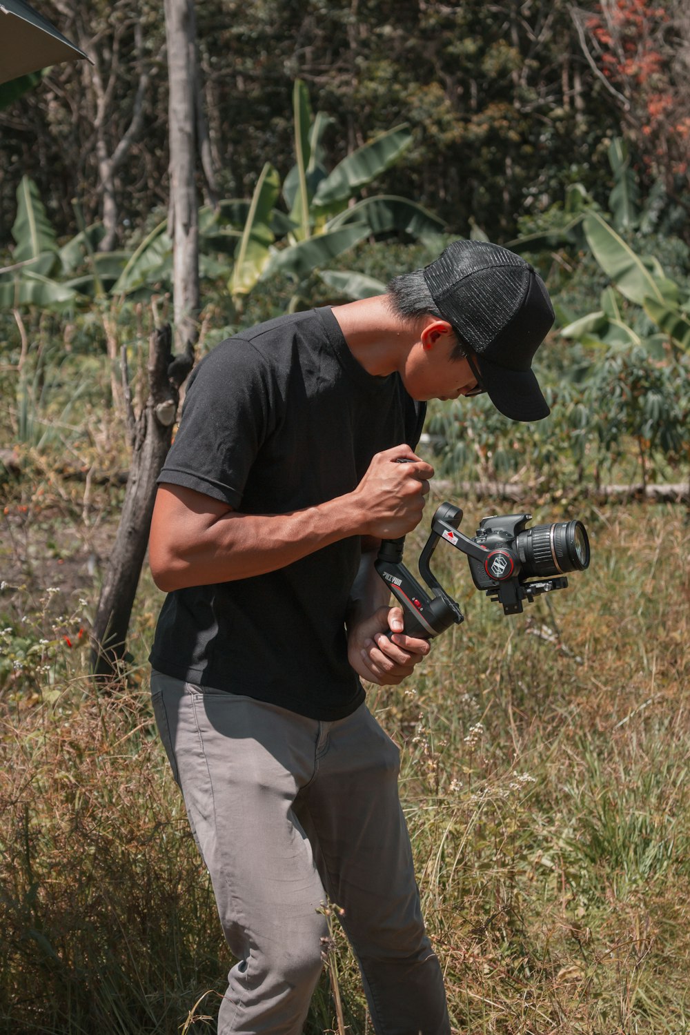 man in black crew neck t-shirt and beige pants holding black dslr camera