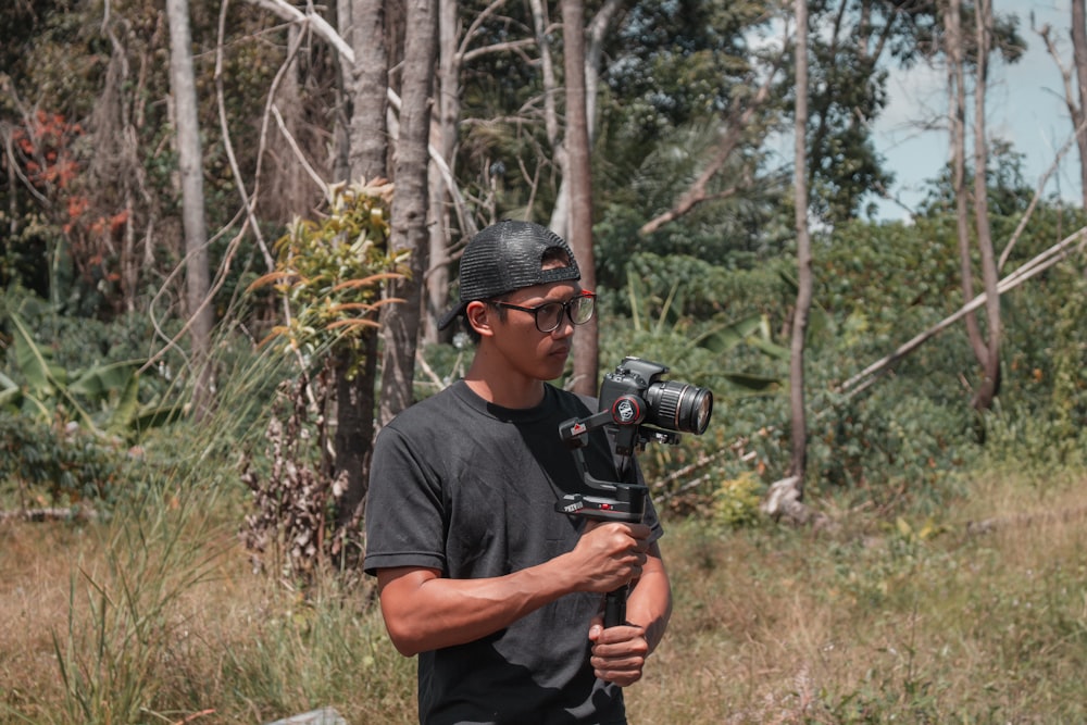 man in black crew neck t-shirt holding black dslr camera