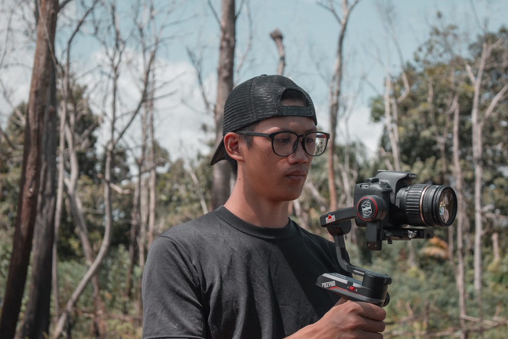 man in gray crew neck shirt holding black dslr camera