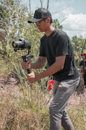 man in black crew neck t-shirt and gray pants holding black dslr camera