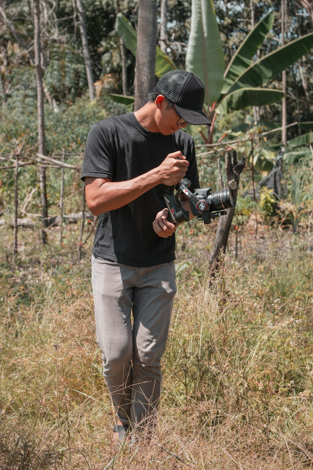 man in black t-shirt and brown pants holding black dslr camera