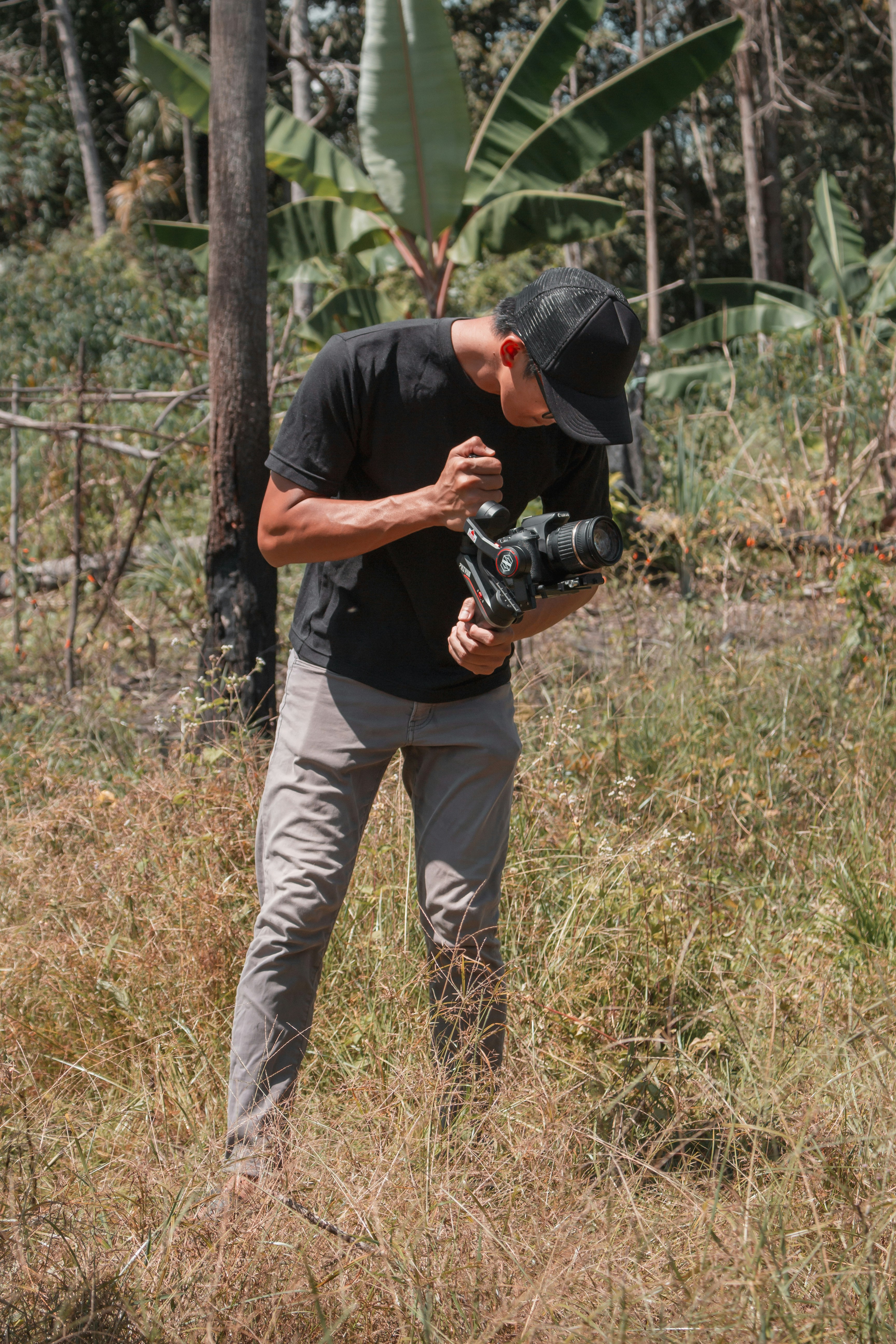 man in black t-shirt and brown pants holding black dslr camera