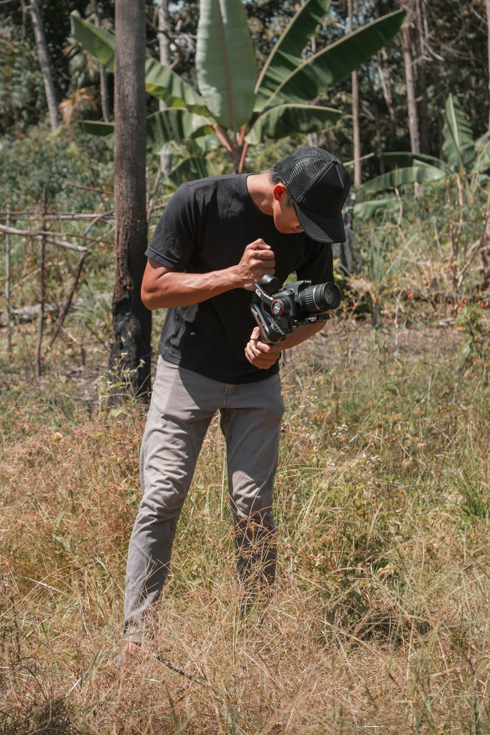 man in black t-shirt and brown pants holding black dslr camera