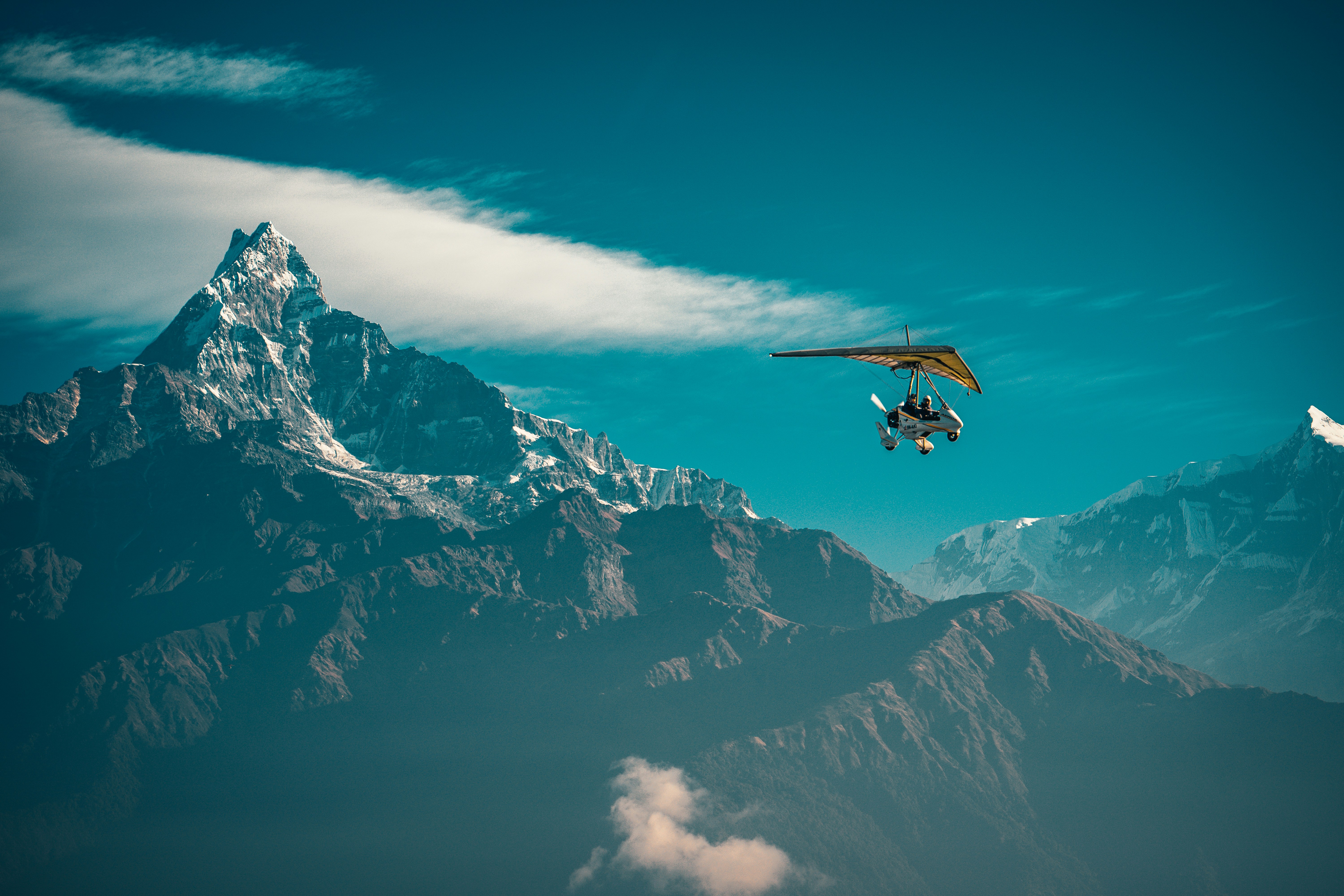 black and white mountain under blue sky during daytime, Lightweight aircraft above valley Himalayn mountain near Machapuchare Mardi Himal track in the Himalaya mountains
