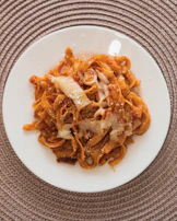 A colorful plate of malloreddus pasta with rich tomato sauce and pecorino cheese.