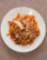 A warm plate of parmegiana with melted cheese and tomato sauce, garnished with basil.