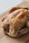 A roasted chicken with golden brown, crispy skin, seasoned with herbs, and placed on a wooden cutting board.