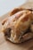 A roasted chicken with golden brown, crispy skin, seasoned with herbs, and placed on a wooden cutting board.