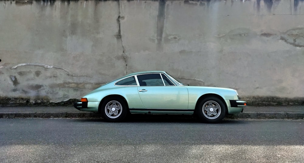 silver coupe parked beside gray concrete wall