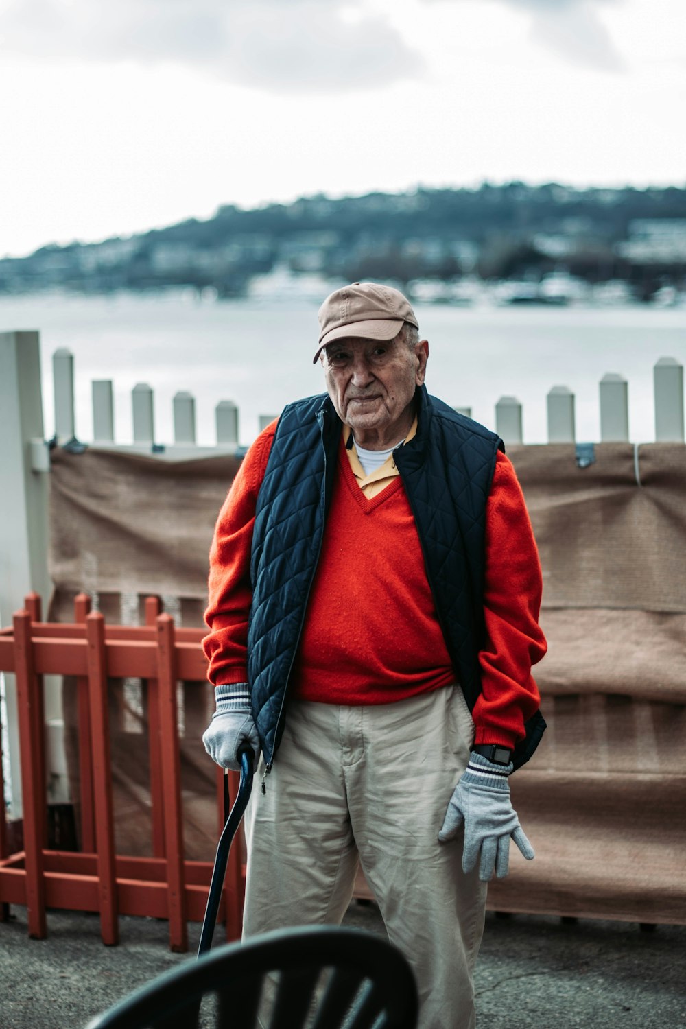 man in red and gray jacket and gray pants standing near red railings during daytime