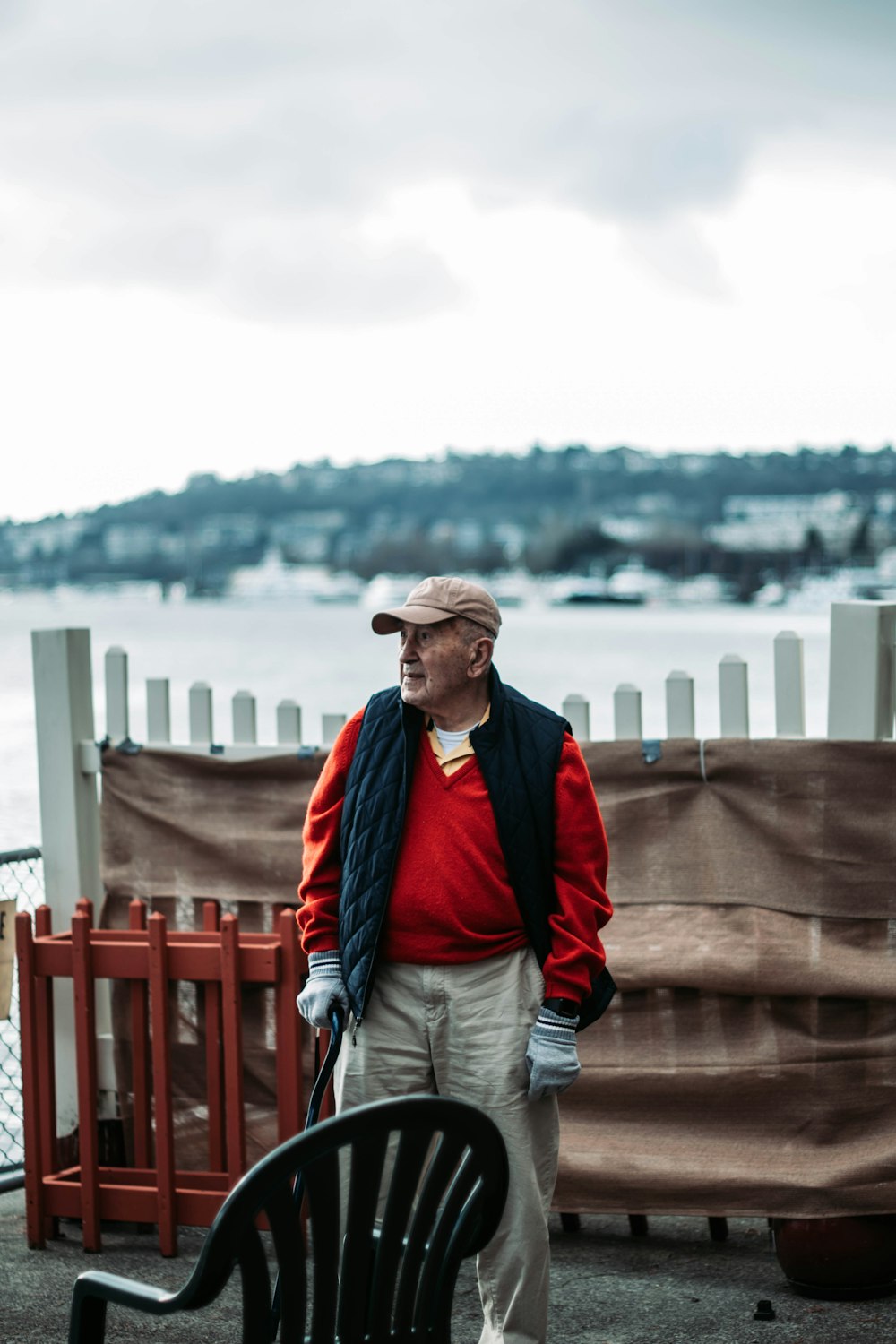 man in red jacket and gray pants standing on wooden dock during daytime
