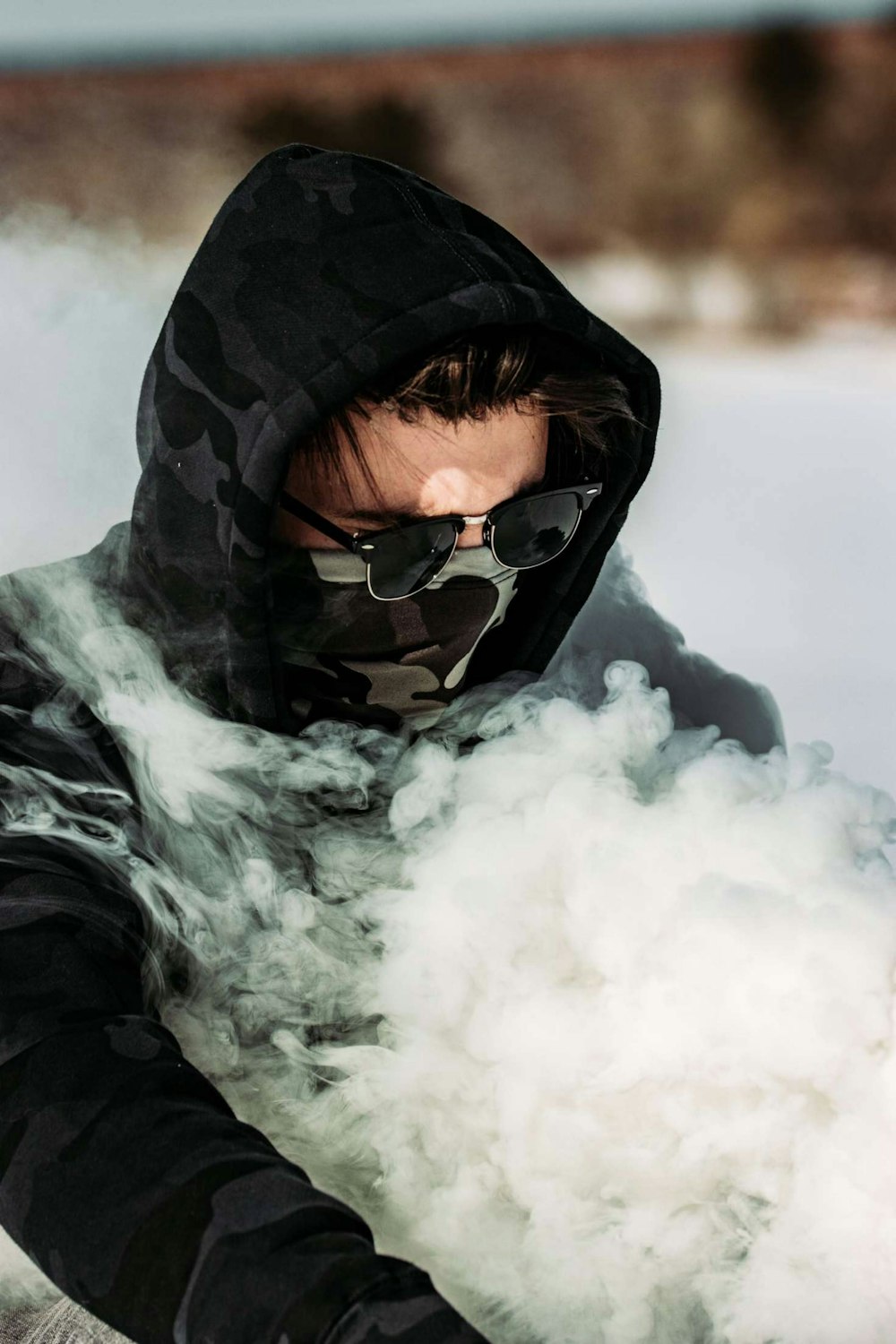 man in black hoodie wearing black sunglasses covered with white smoke