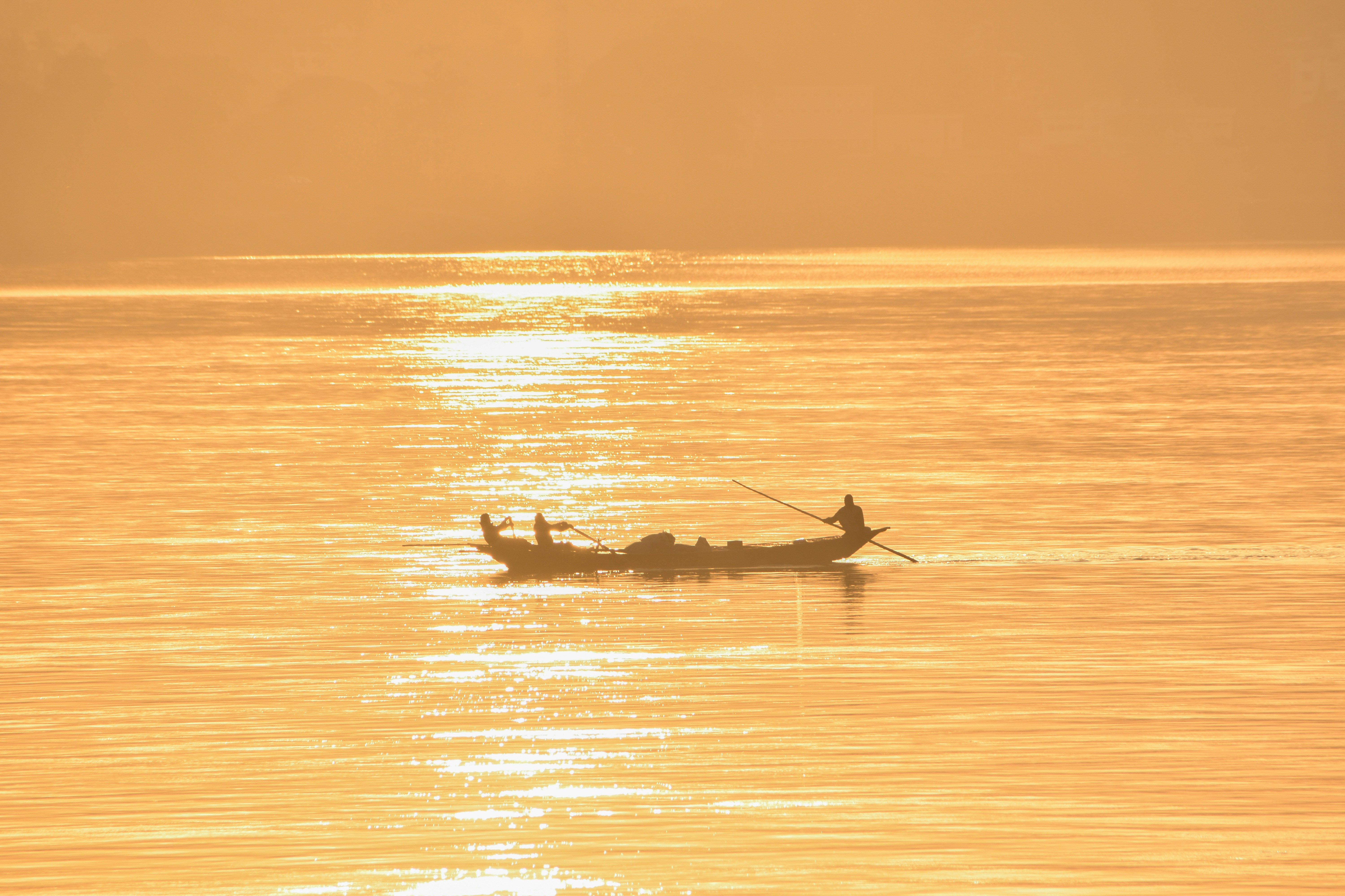 Silhouette of two people riding on a boat on the sea during sunset