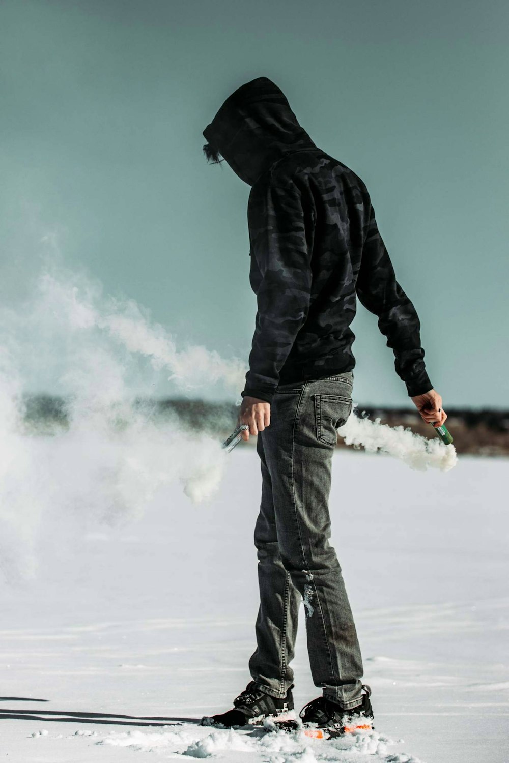 man in black jacket and blue denim jeans standing on snow covered ground during daytime